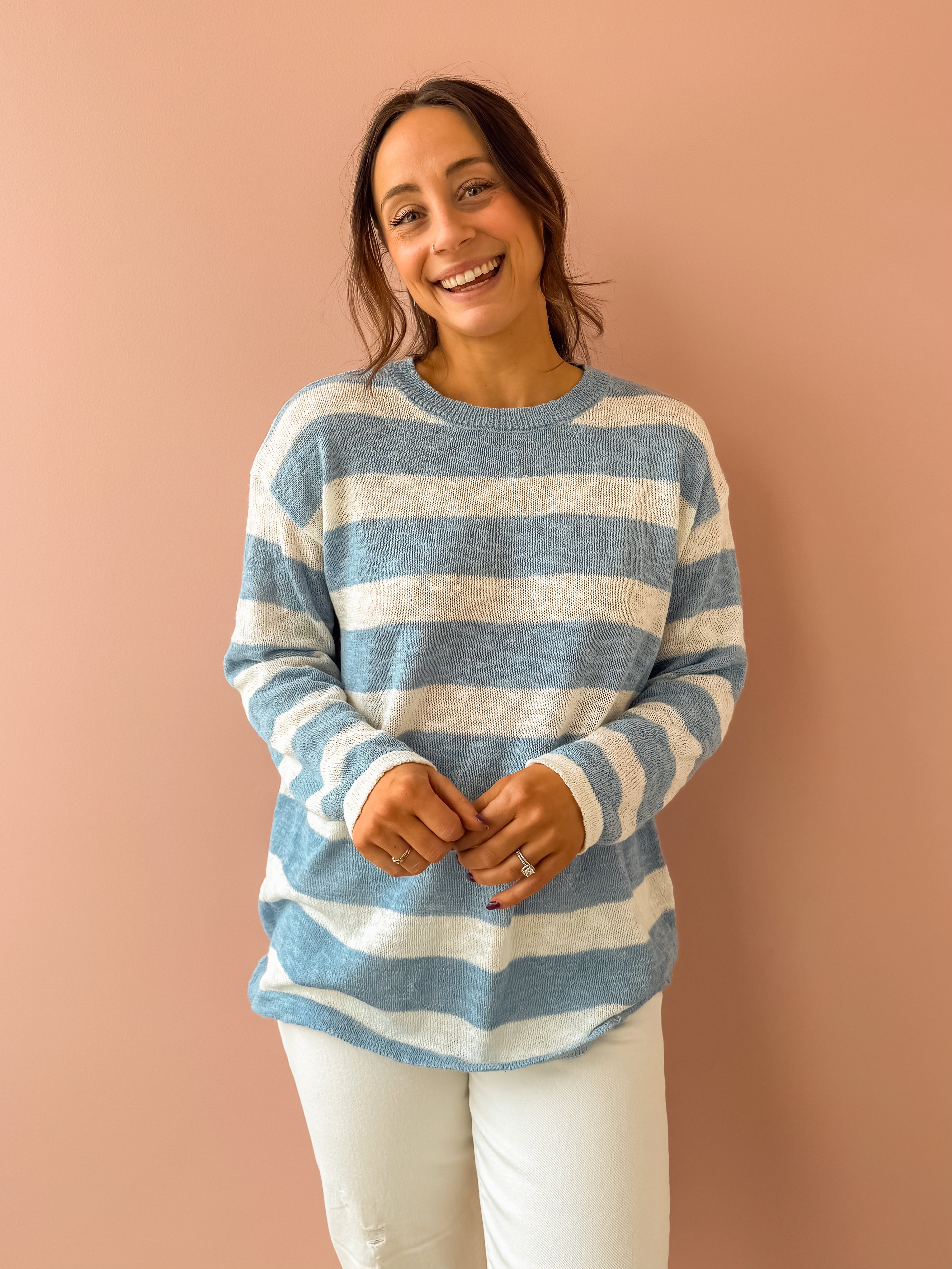 Woman wearing a blue and white striped sweater against a pink background