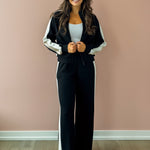 Woman wearing a black and white tracksuit against a pink wall