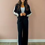 Woman wearing a black and white tracksuit against a pink wall