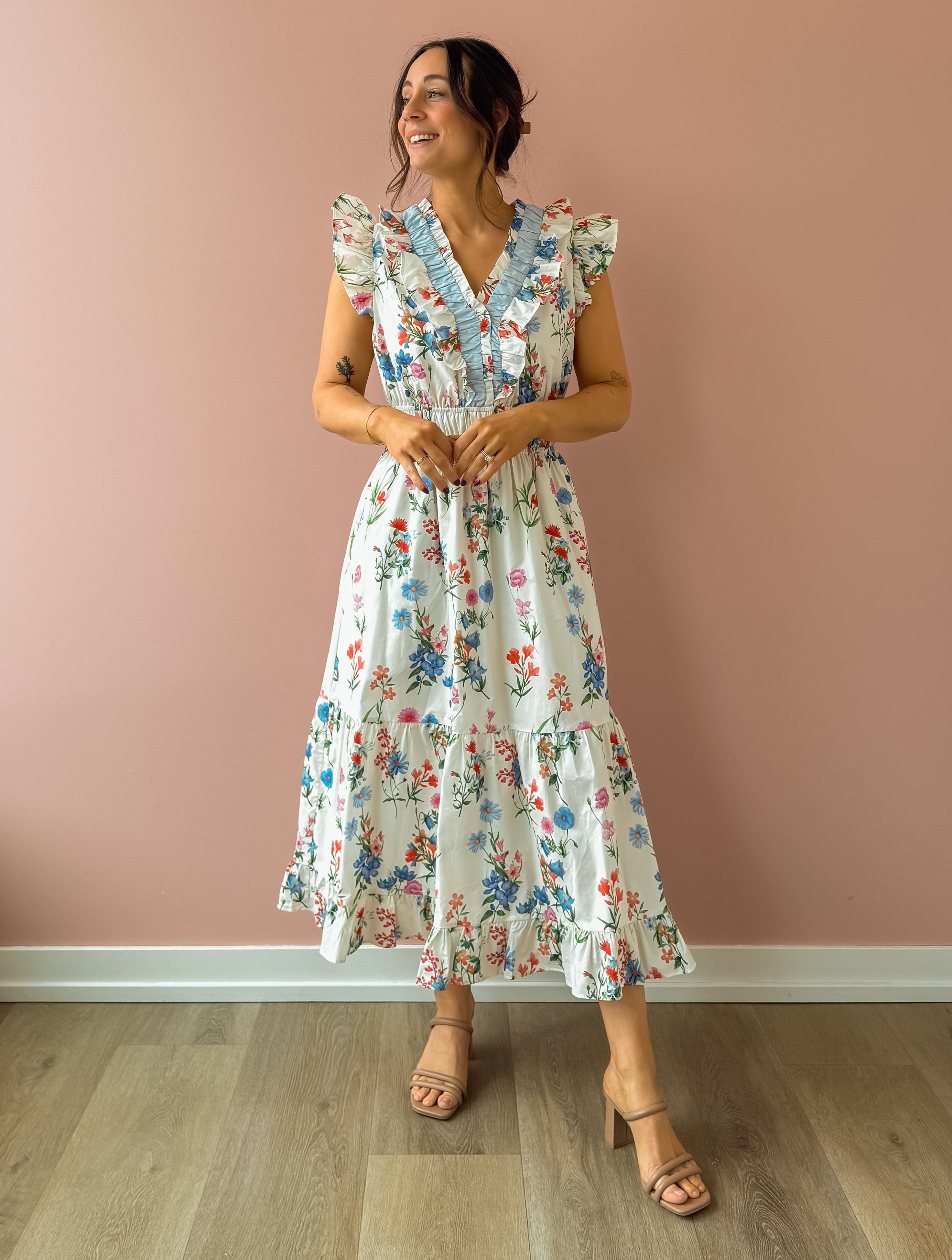Woman wearing a floral dress against a pink wall
