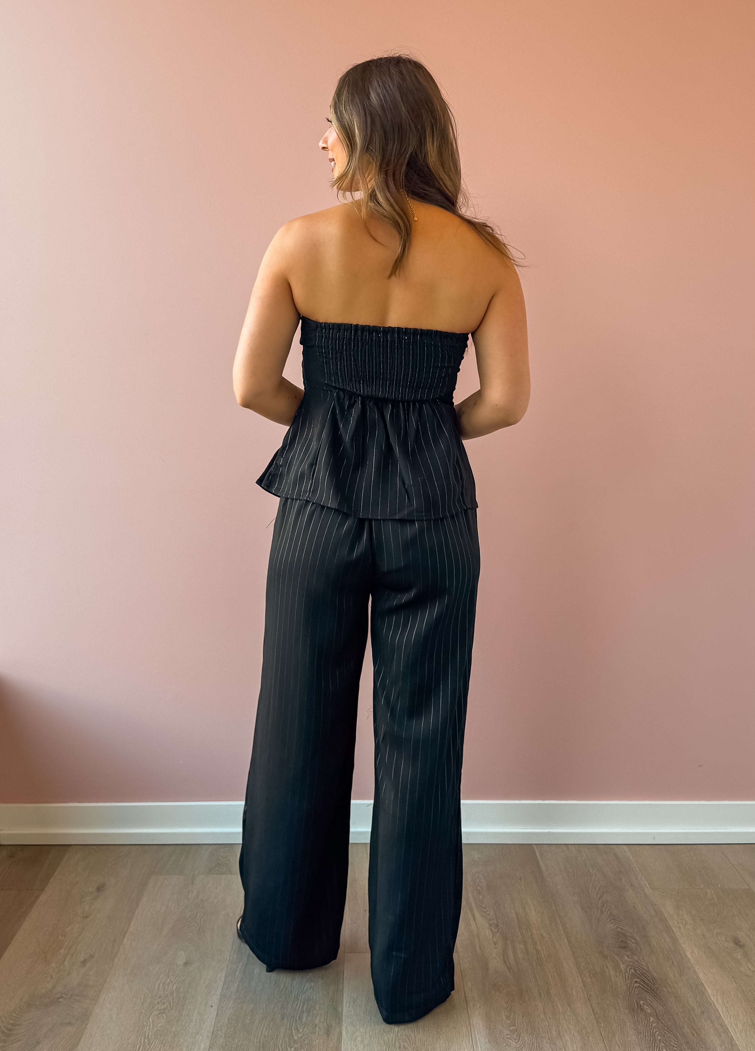 Sadie & Sage Gilded Evening Pinstripe Pants in black with silver pinstripes, full-length back view.