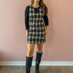 Sadie & Sage Served Up Stretch Plaid Mini Dress in black and tan plaid, front view, layered over a black long sleeve top.